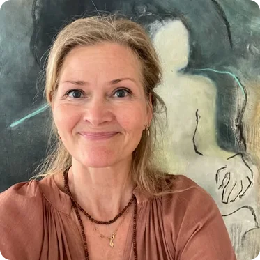 Underviser på Academy Copenhagen Charlotte Jonsson smiler med maleri i baggrunden
